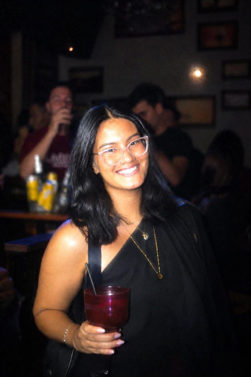 AI-generated: CCD Night Flash AI filter result: smiling woman with a drink on a night out at a bar