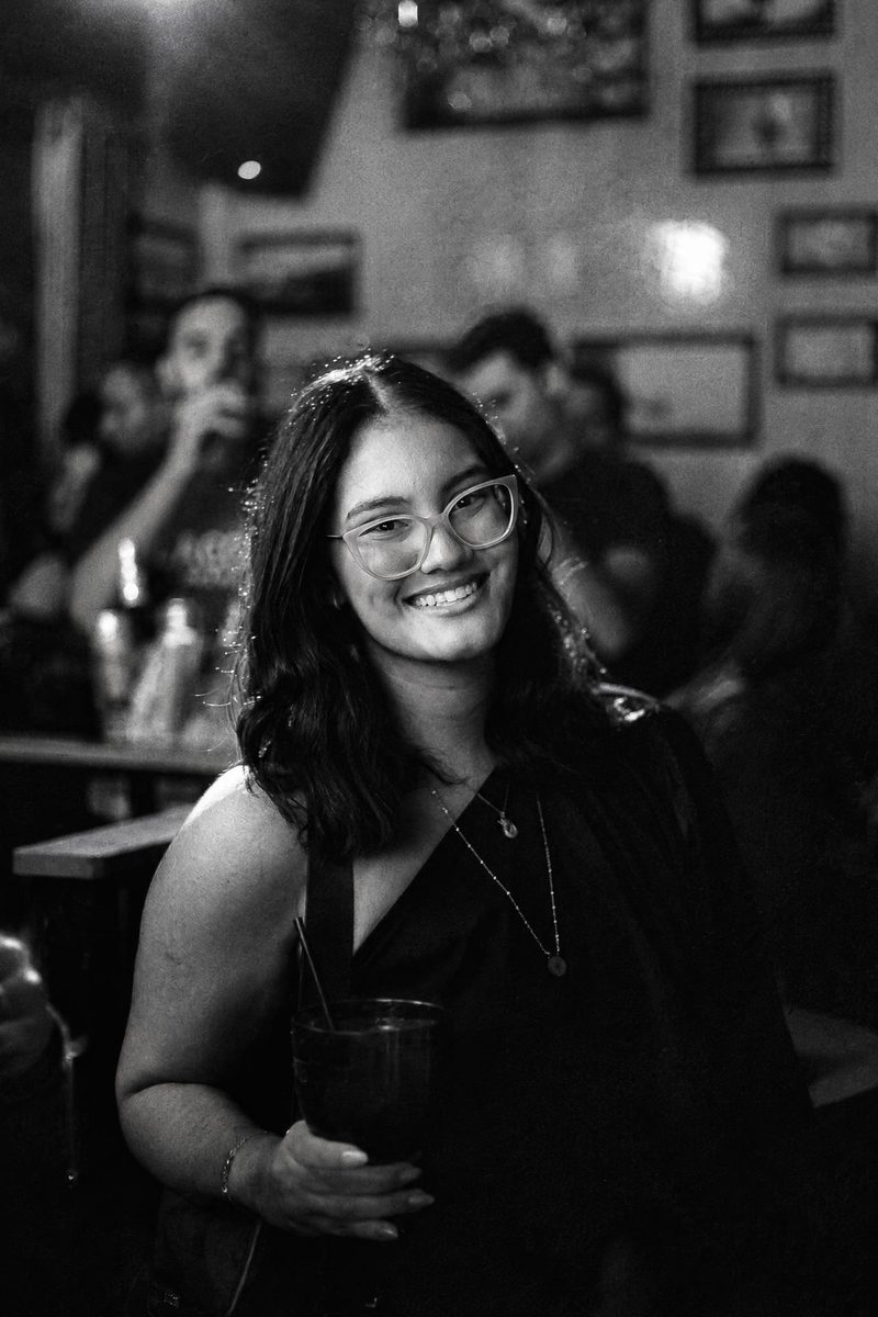 AI-generated: Classic B&W Film AI filter result: smiling woman with a drink on a night out at a bar