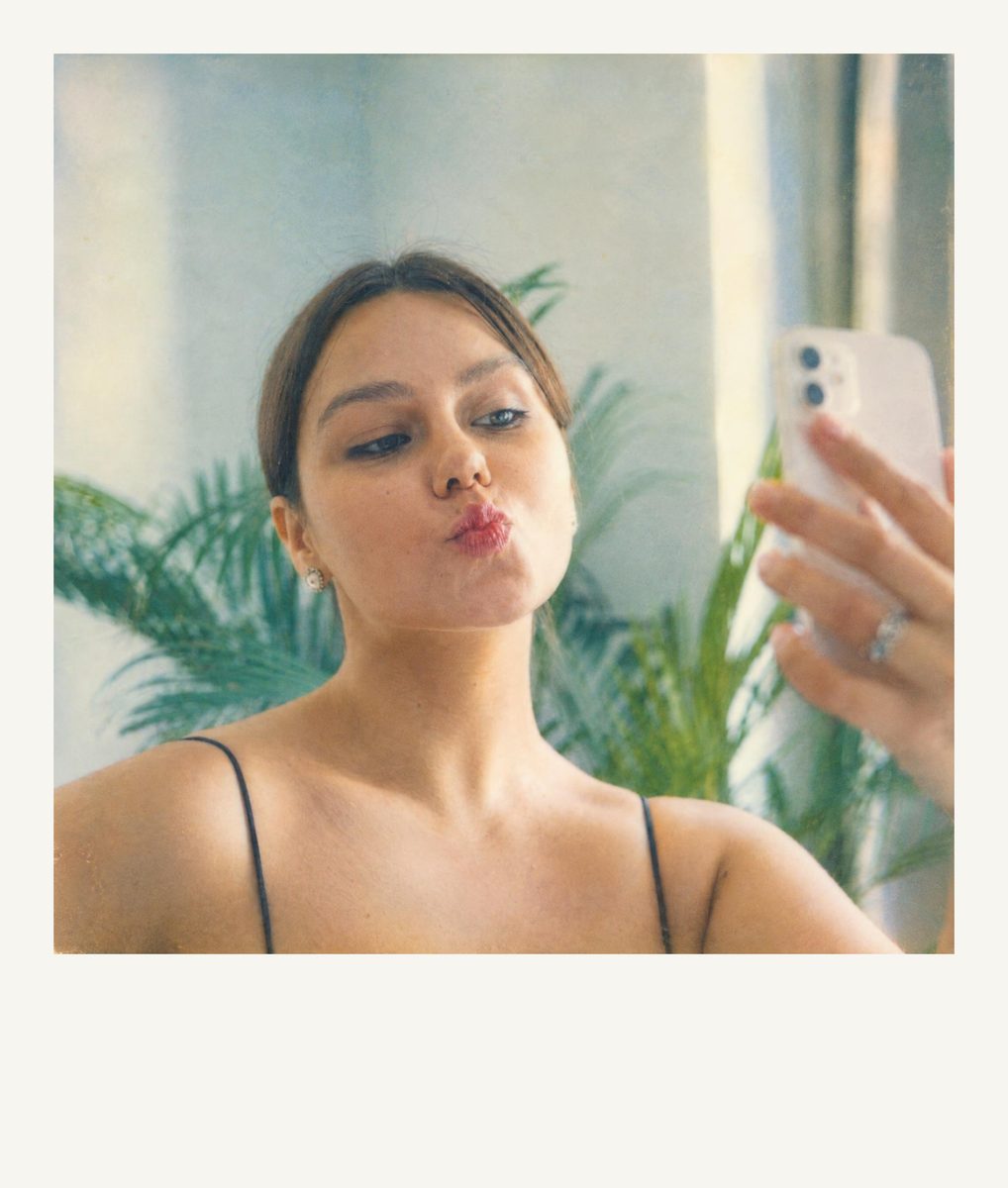AI-generated: Instant Film Frame AI filter result: woman in a black top taking a mirror selfie