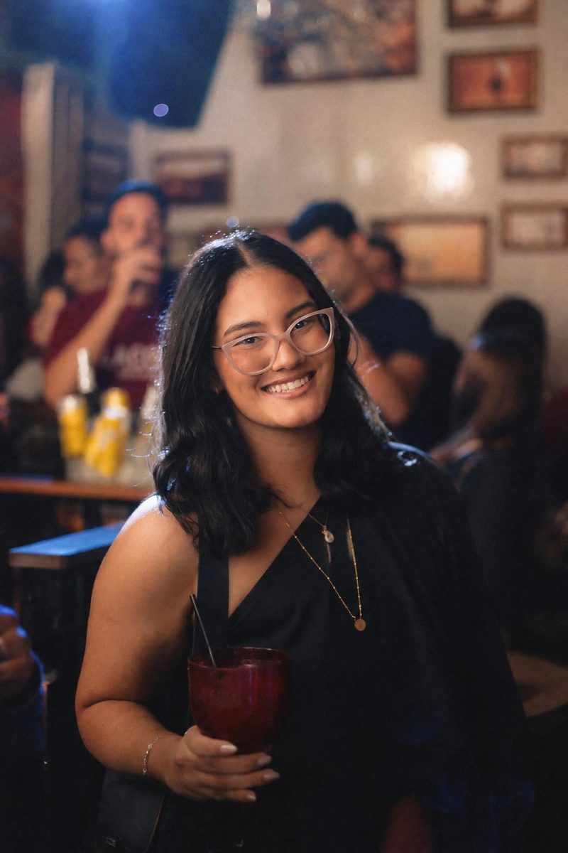 AI-generated: Warm Portrait 400 AI filter result: smiling woman with a drink on a night out at a bar