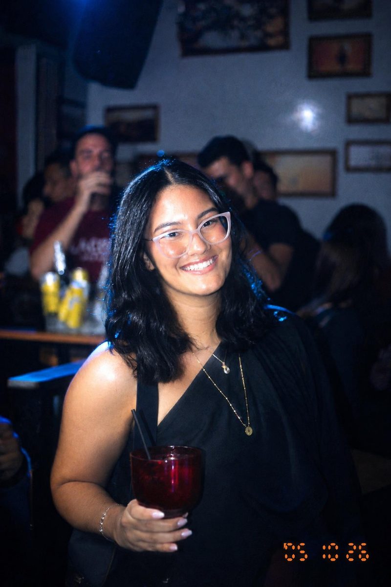 AI-generated: Y2K Compact Digicam AI filter result: smiling woman with a drink on a night out at a bar